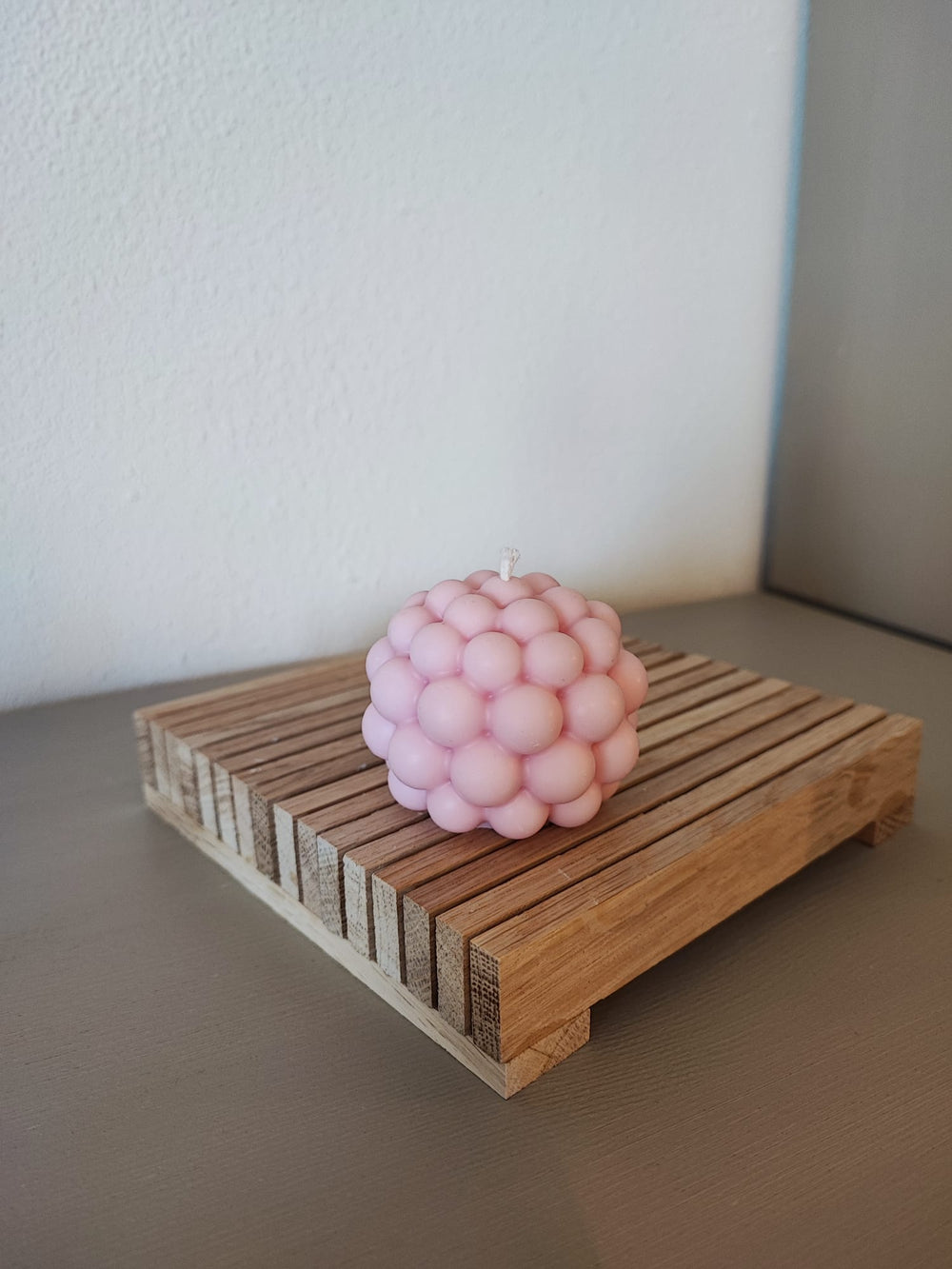 Rapswachskerze_handgegossen_Bubblekugel_rosa_auf_Holzbrett_Frontansicht
