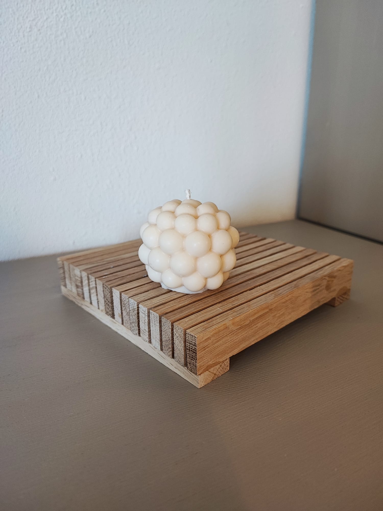 Rapswachskerze_handgegossen_Bubblekugel_weiss_auf_Holzbrett_Frontansicht