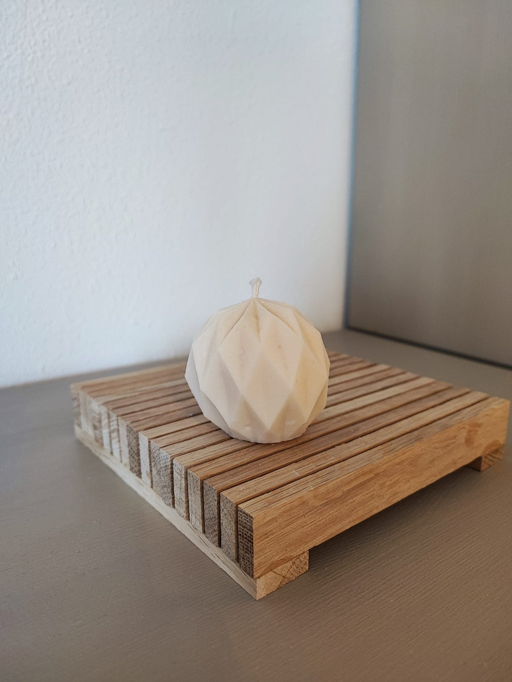 Rapswachskerze_handgegossen_Netzkugel_weiss_Frontansicht_auf_Holzbrett
