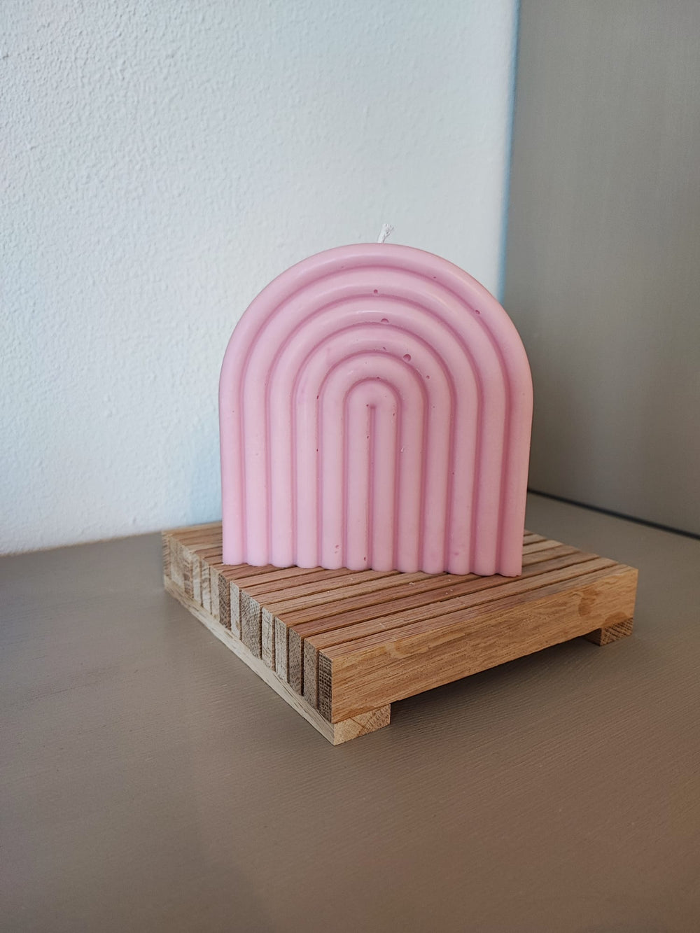 Rapswachskerze_handgegossen_Regenbogen_rosa_auf_Holzbrett_Frontansicht_1