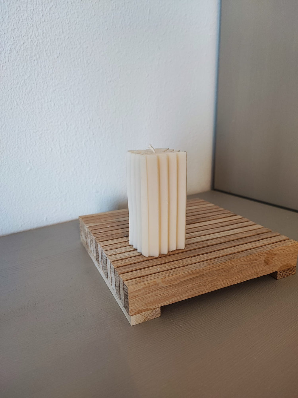 Rapswachskerze_handgegossen_Saeule_Mel_weiss_Frontansicht_auf_Holzbrett