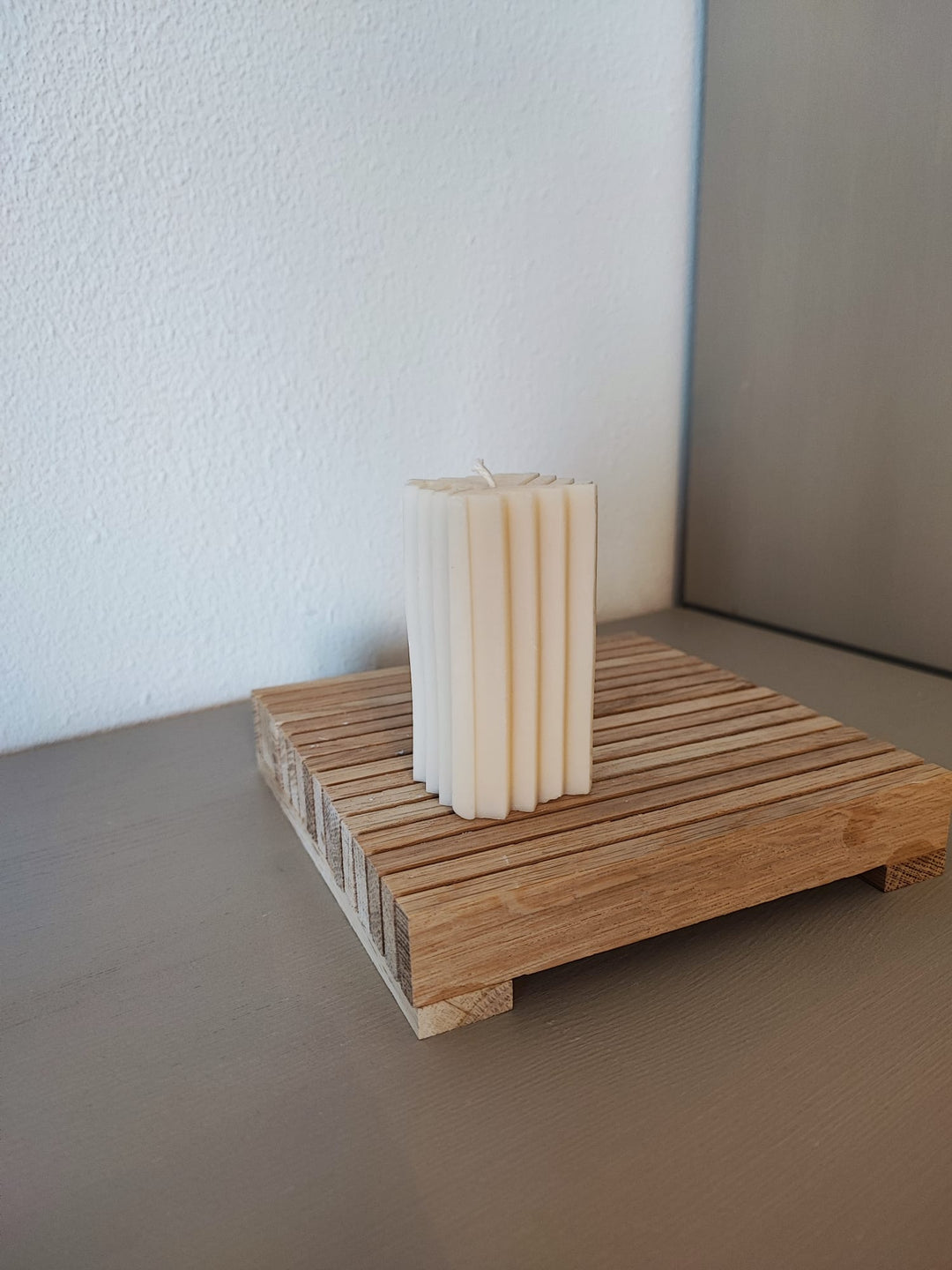 Rapswachskerze_handgegossen_Saeule_Mel_weiss_Frontansicht_auf_Holzbrett