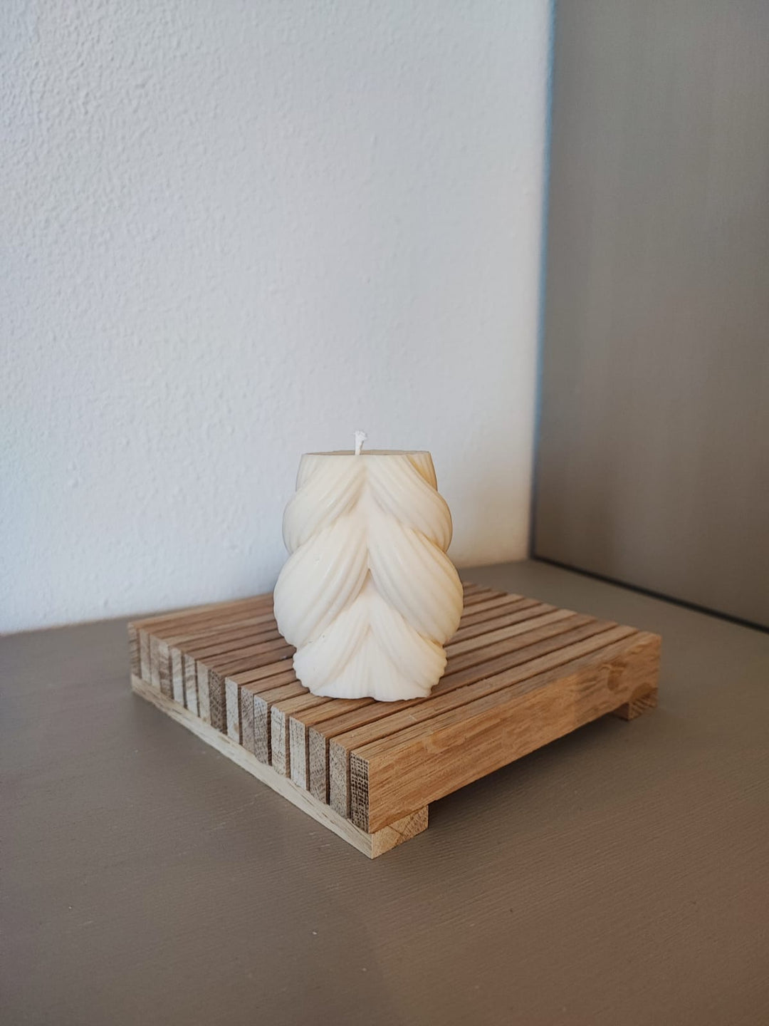 Rapswachskerze_handgegossen_Strickknaeul_weiss_auf_Holzbrett_Frontansicht