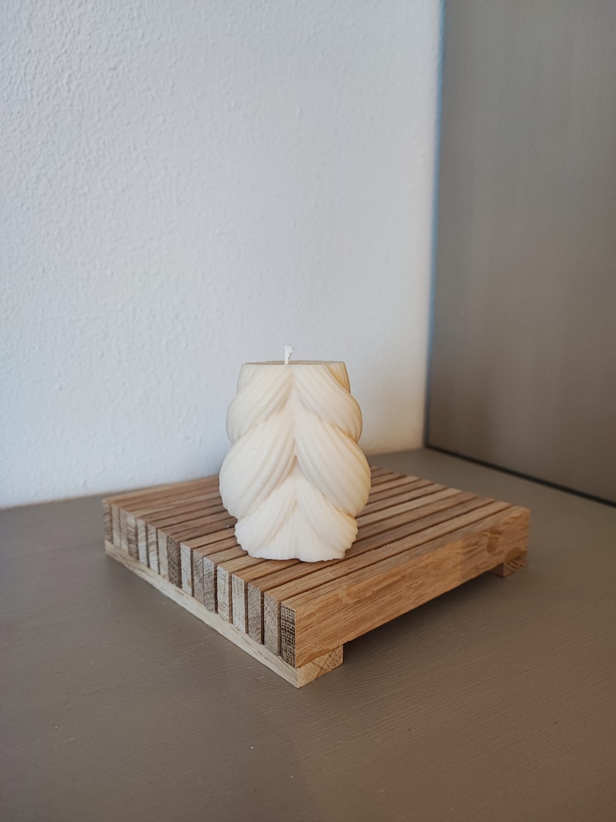 Rapswachskerze_handgegossen_Strickknaeul_weiss_auf_Holzbrett_Frontansicht