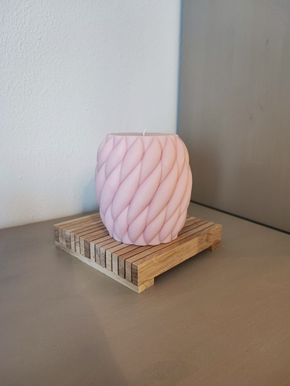 Rapswachskerze_handgegossen_Wollknaeul_Gross_rosa_auf_Holzbrett_Frontansicht