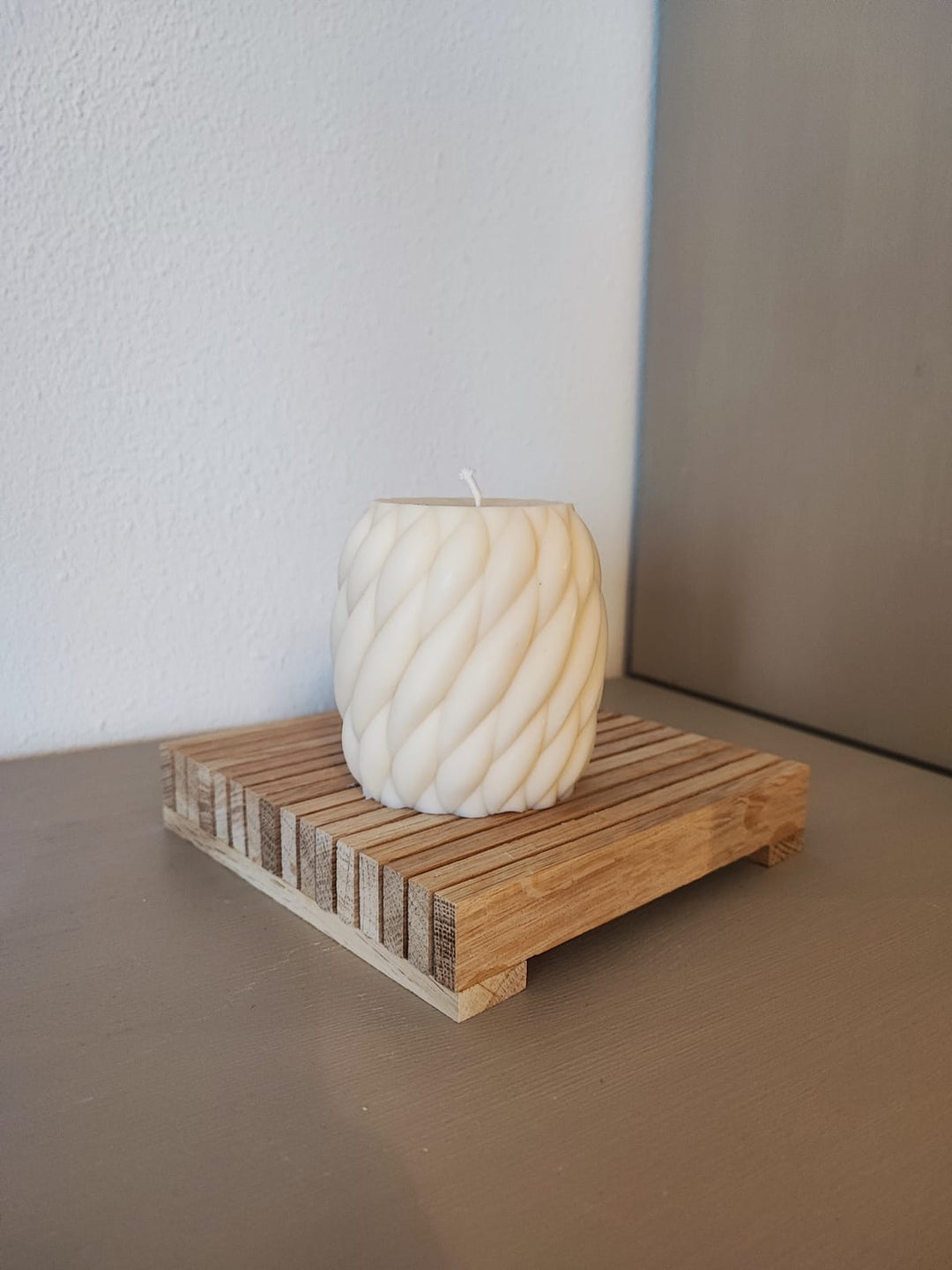 Rapswachskerze_handgegossen_Wollknaeul_mittel_weiss_auf_Holzbrett_Frontansicht