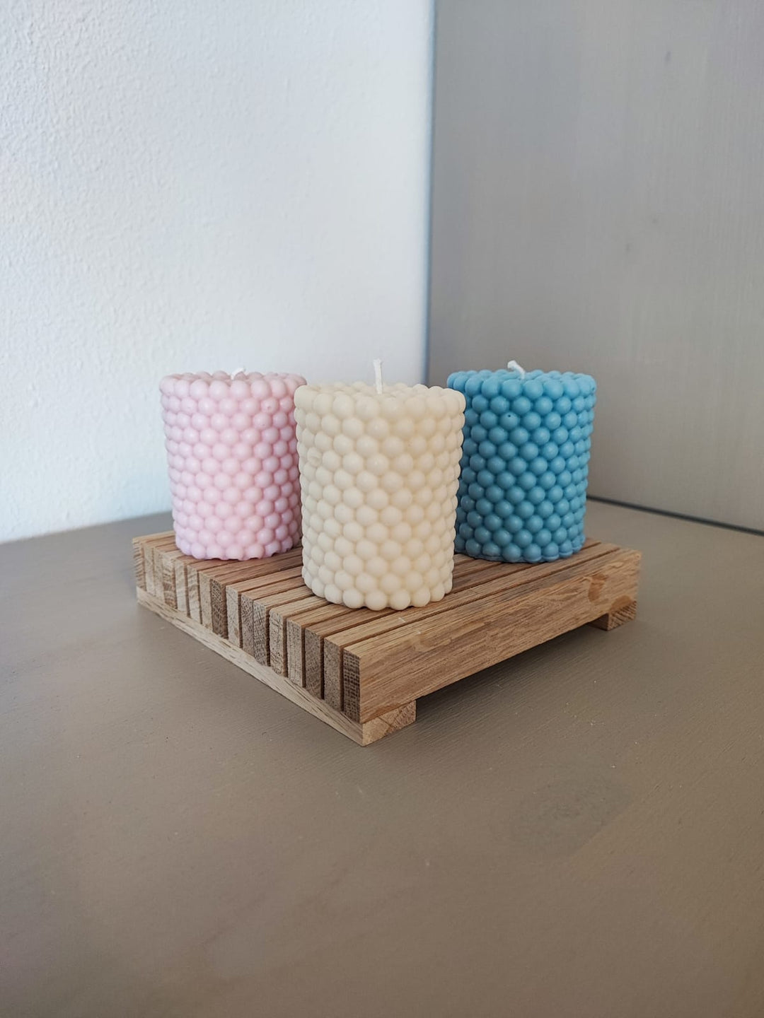 Rapswachskerze_handgegossen_set_weiss_rosa_tuerkis_auf_holzbrett_frontansicht