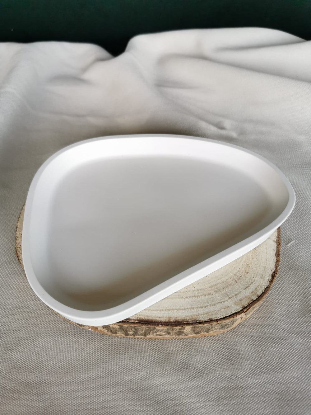 Handgefertigte, weiße Keramikschale in organischer Form, auf Holzuntergrund platziert – minimalistisches Dekotablett für moderne Wohnräume