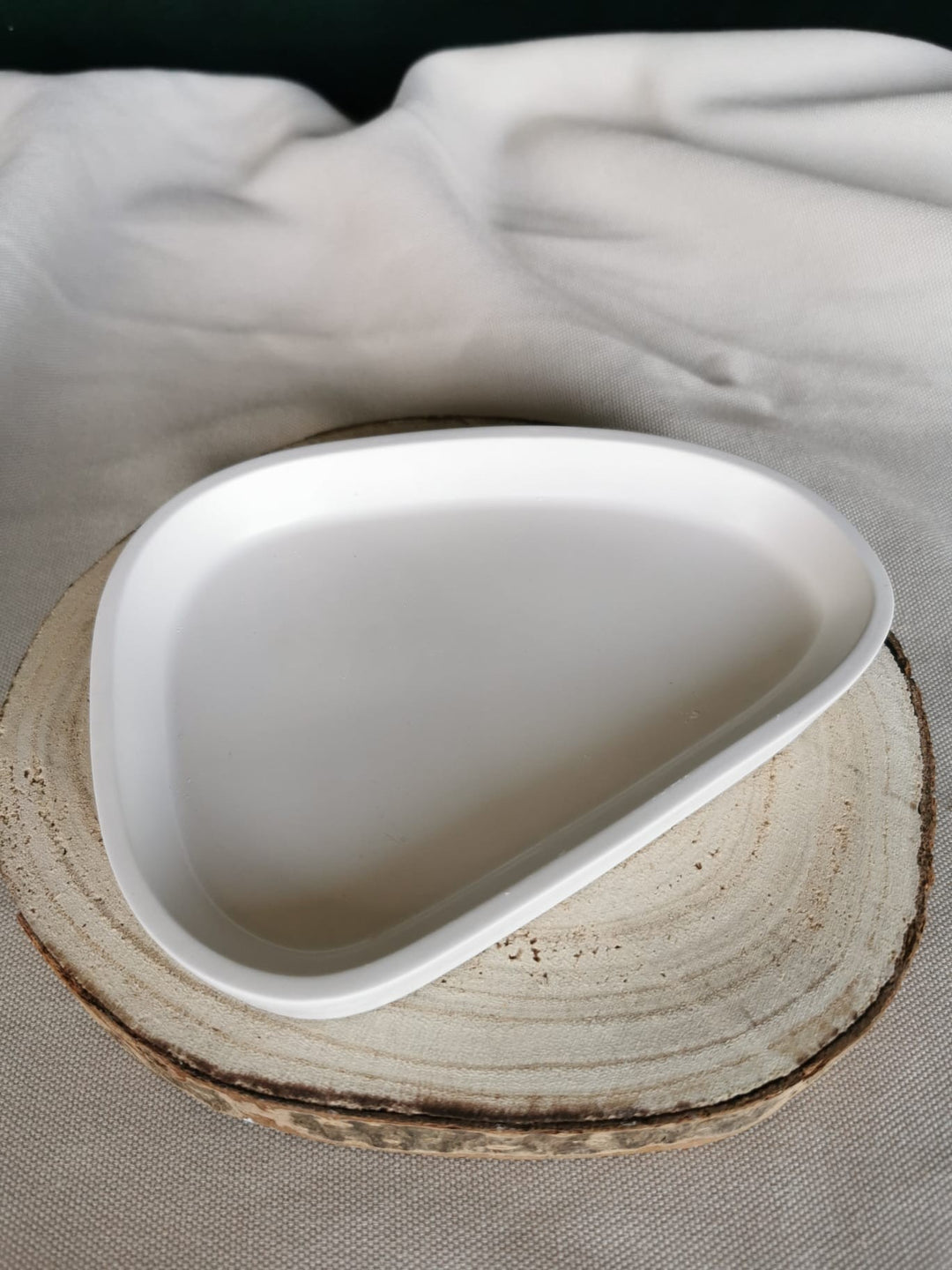 Handgefertigte Ablageschale aus weißer Keramik in moderner, organischer Form – minimalistisches Dekotablett auf Holzuntergrund