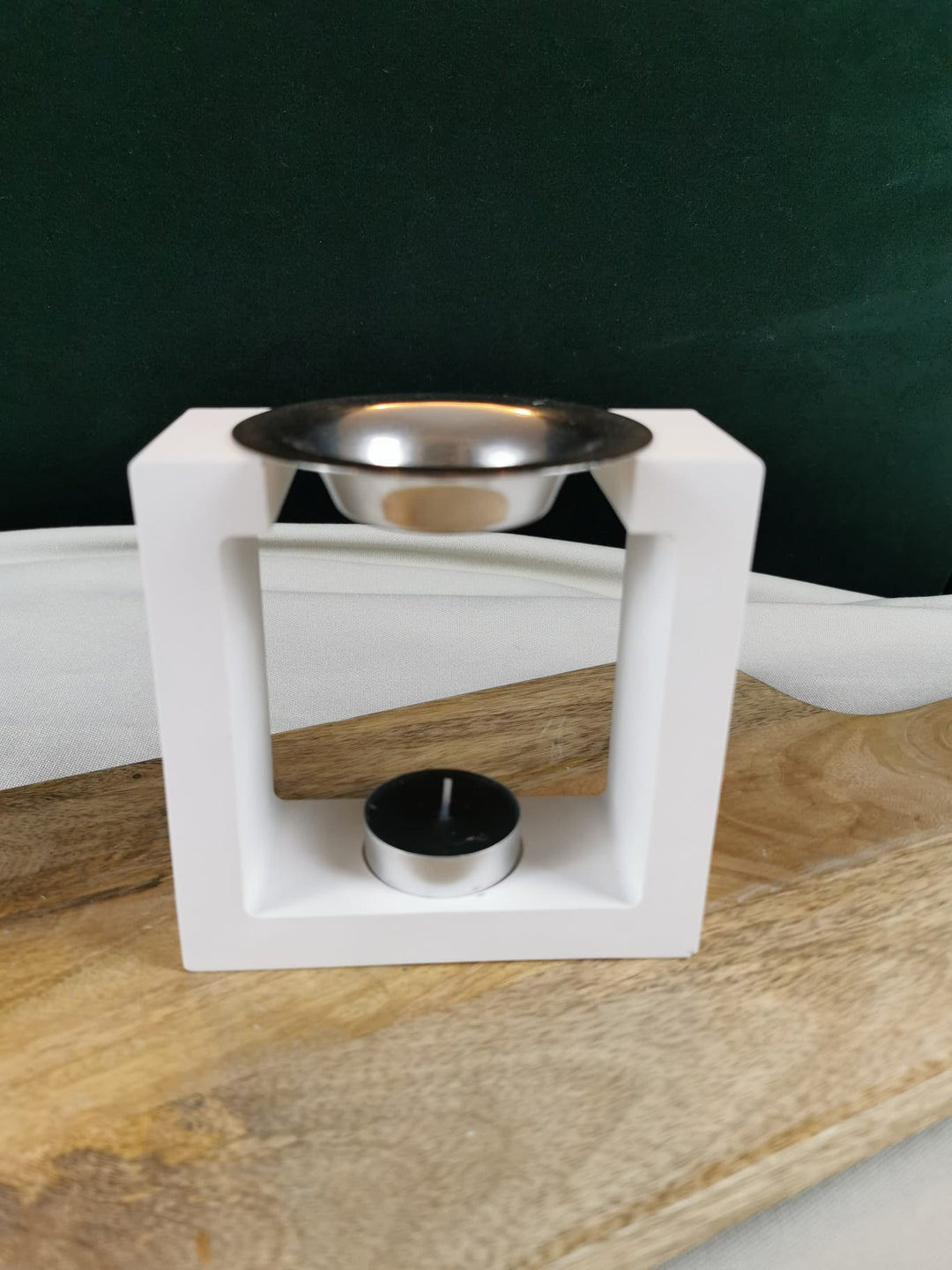 „Minimalistischer weißer Keramik-Aromabrenner mit Metallschale für Duftöle und Duftwachse auf Holzhintergrund“