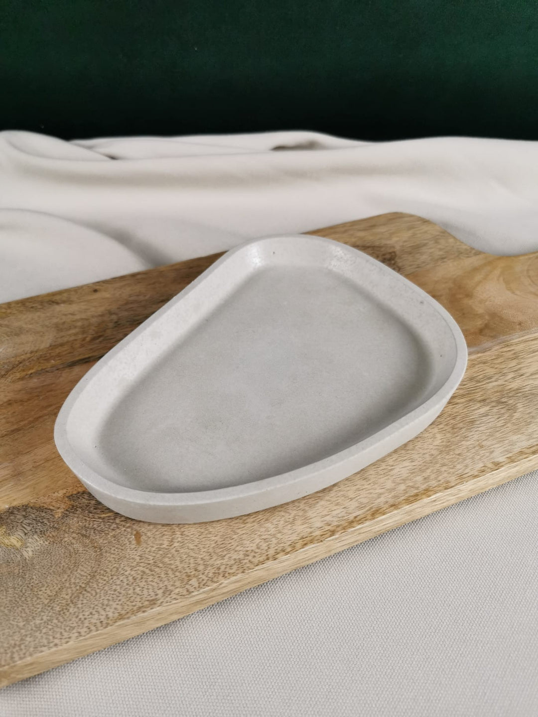 „Handgefertigte Beton-Schale in organischer Tropfenform auf Holzbrett – minimalistische graue Deko-Ablage