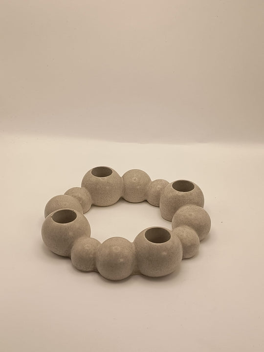Runder, moderner Kerzenhalter aus Beton in organischer Kugelform, mit vier integrierten Öffnungen für Stabkerzen, auf hellem Hintergrund fotografiert