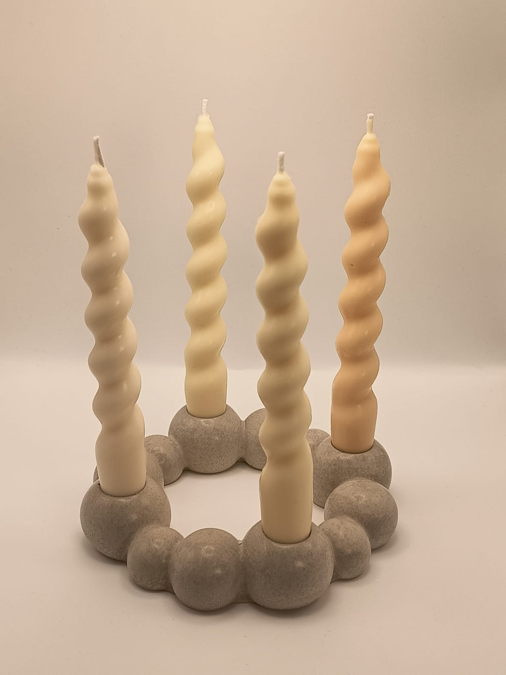 Moderner runder Kerzenkranz aus grauem Beton mit vier handgegossenen, gedrehten Rapswachskerzen in Naturtönen, mit Baumwolldocht. Minimalistische, nachhaltige Tischdekoration