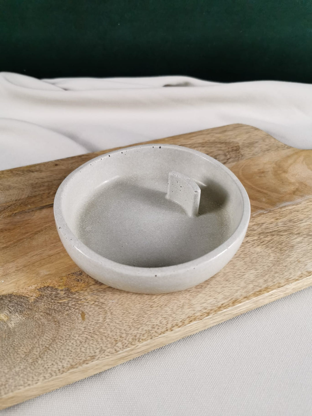 Handgefertigte runde Beton-Schale in sanftem Grau, ideal als Ablage oder Räucherhalter, dekorativ auf Holzbrett präsentiert.