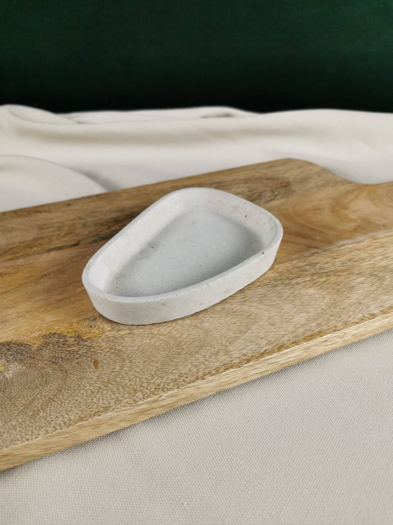 Handgefertigte kleine Betonschale in organischer Form auf Holzbrett – minimalistische Dekoration aus Beton.