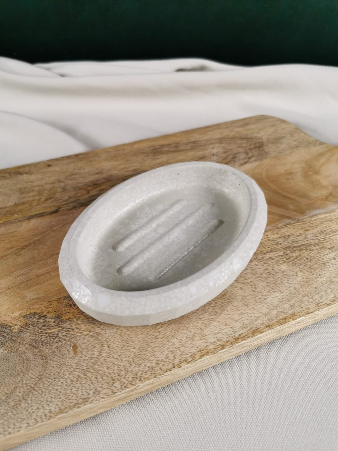 „Ovale handgemachte Seifenschale aus Beton mit Rillen, minimalistisches Design auf Holzunterlage.“