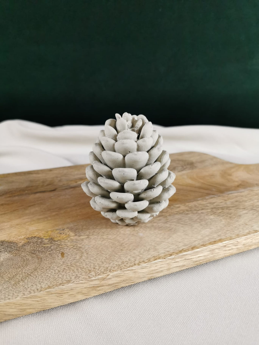 Handgemachter Beton-Tannenzapfen in natürlicher grauer Optik – dekoratives Winter- und Weihnachts-Dekoobjekt auf Holzbrett