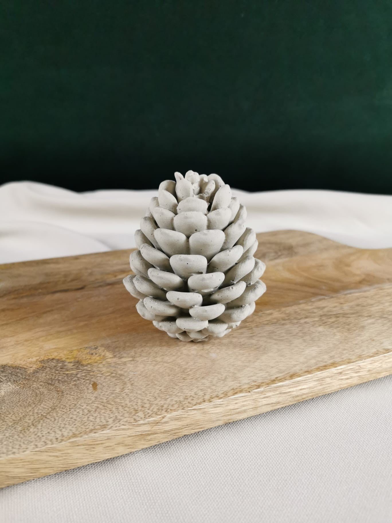 Handgemachter Beton-Tannenzapfen in natürlicher grauer Optik – dekoratives Winter- und Weihnachts-Dekoobjekt auf Holzbrett