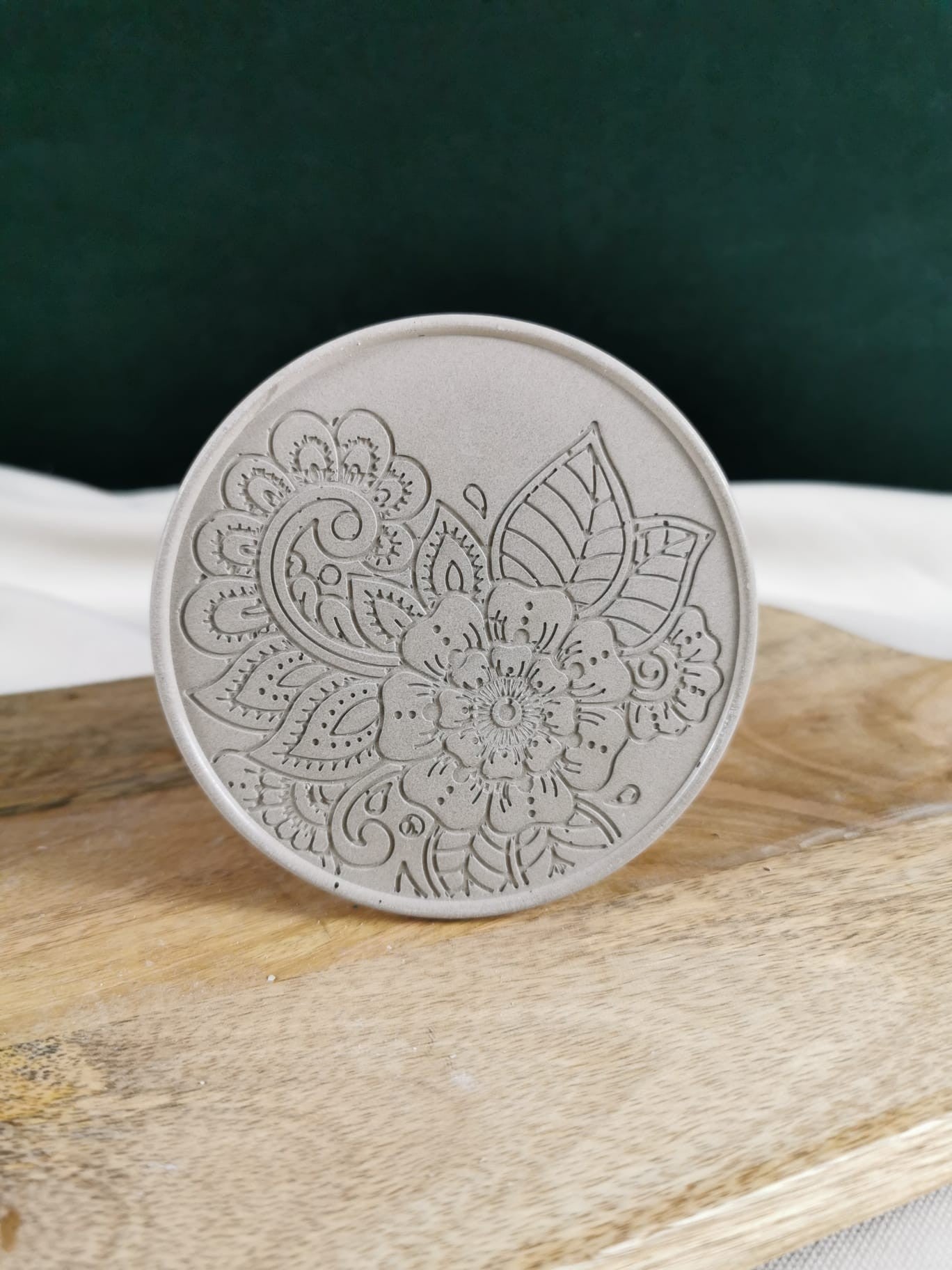 „Runder Beton Untersetzer mit detaillierter floraler Mandala-Gravur auf Holzuntergrund – handgefertigte Deko aus Beton.“