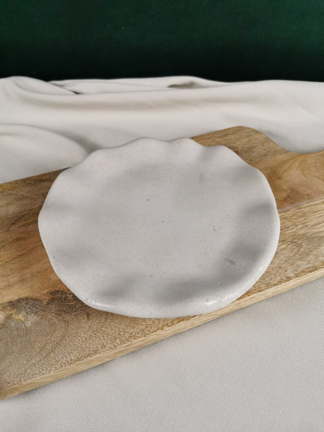 "Handgemachte organische Betonablage in wellenförmigem Design, dekorativ auf einem Holzbrette präsentiert."