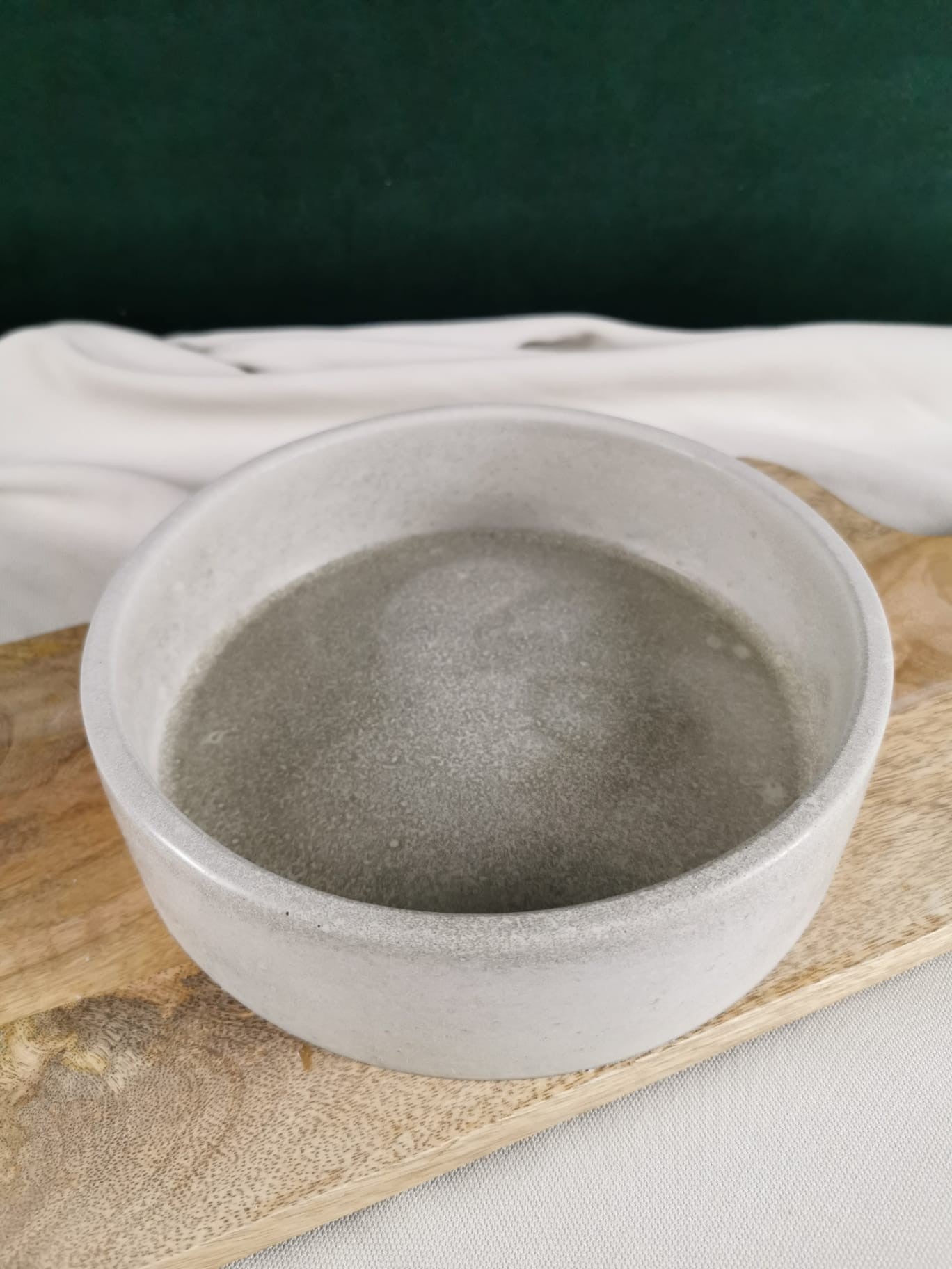 Handgemachte minimalistische Betonschale in hellem Grau, dekorativ auf einem Holzbrett präsentiert – perfekt für Schmuck, Deko, Räucherungen oder Kerzen.