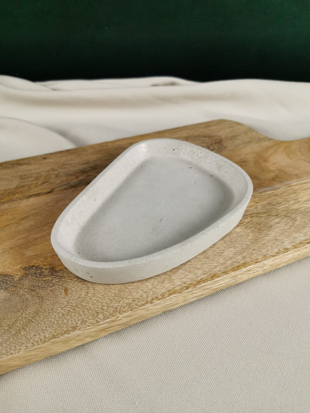 Handgefertigte minimalistische Betonschale in organischer Dreiecksform auf Holzunterlage.