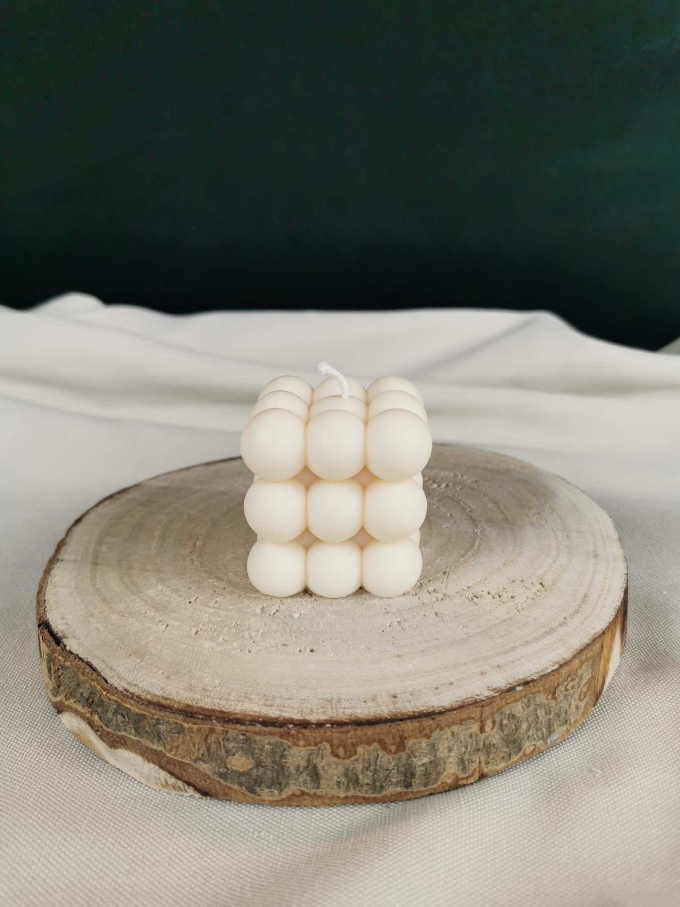 „Handgegossene vegane Bubble Cube Kerze aus naturreinem Rapswachs auf Holzuntergrund – dekorative, moderne Designkerze in Cremeweiß.“