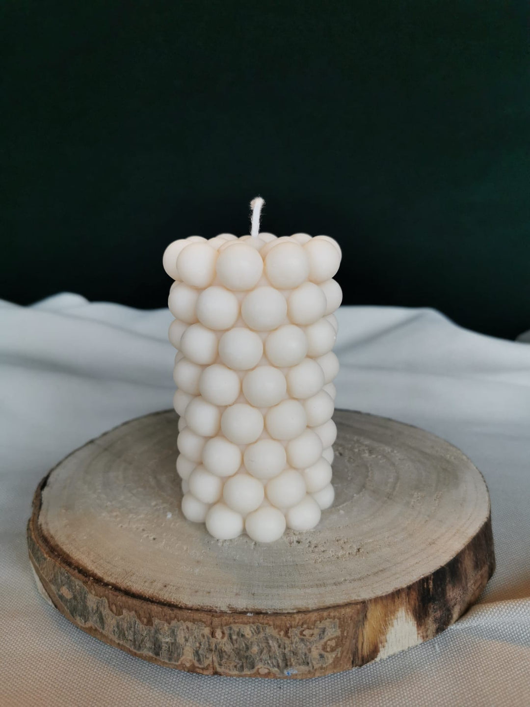 „Handgemachte Bubble-Tower-Kerze aus natürlichem Rapswachs in Cremeweiß, auf Holzplatte dekoriert – moderne vegane Designkerze.“