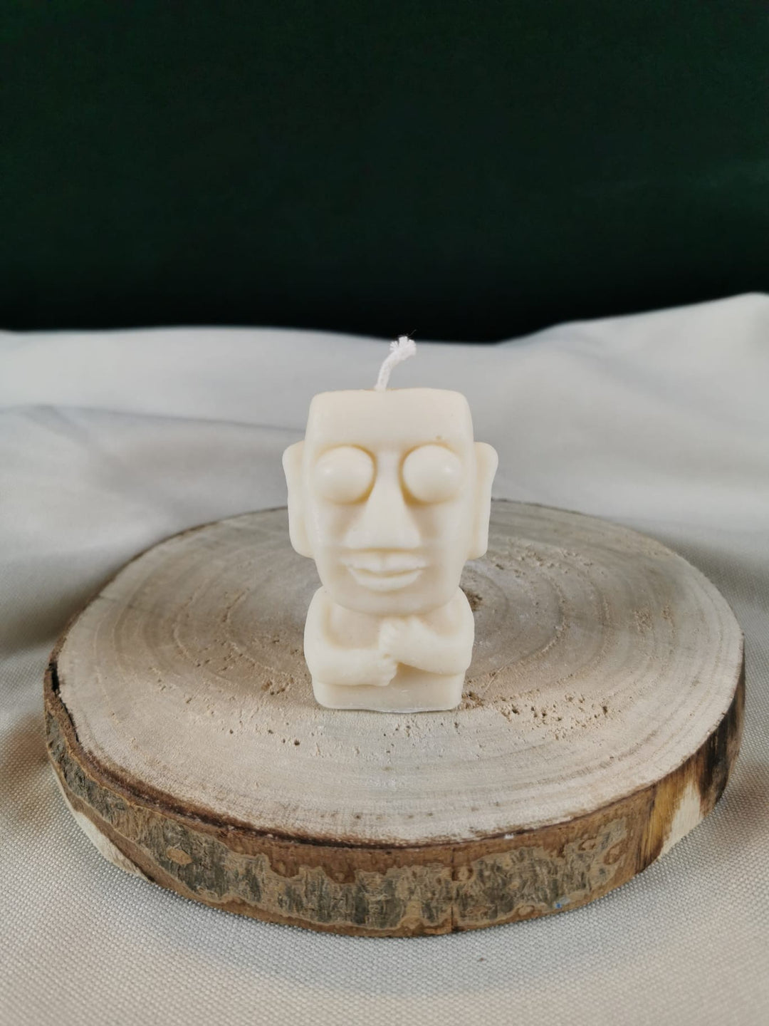 „Handgegossene Buddha- oder Mönch-Kerze aus Rapswachs in Cremeweiß auf Holzunterlage.“