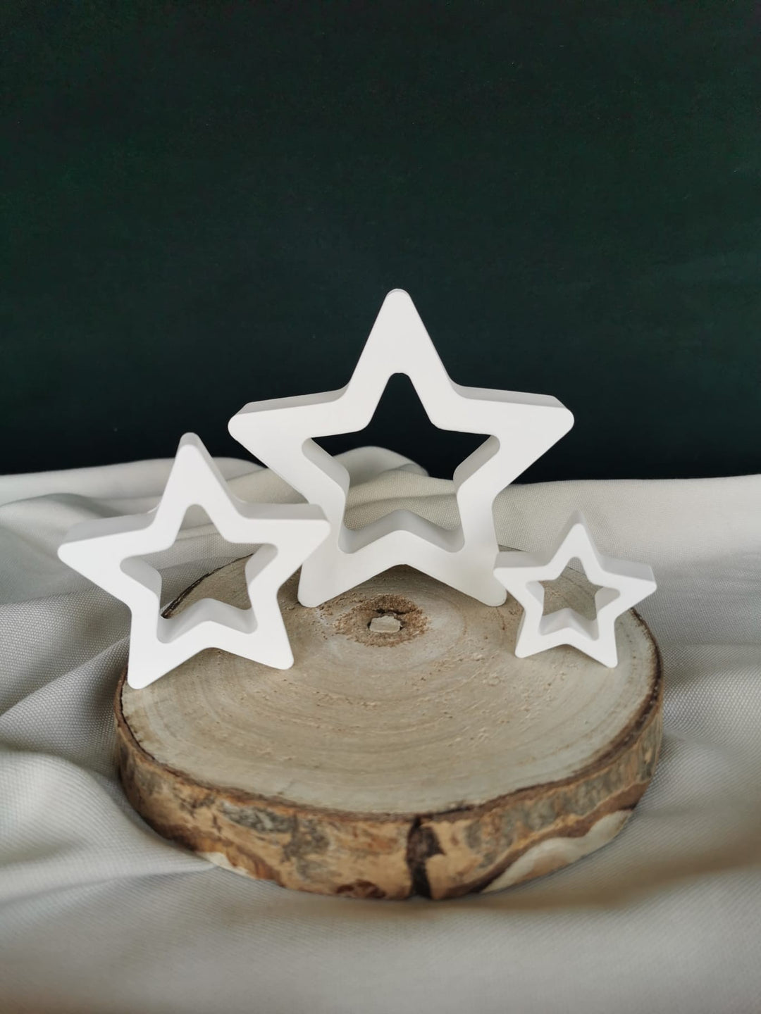 „Weißes 3er-Set hohler Deko-Sterne in verschiedenen Größen, minimalistische Weihnachtsdekoration auf Holzscheibe.“