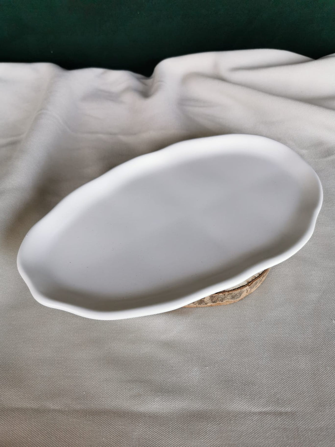 Weiße, handgefertigte flache Keramikschale mit organisch geformtem Rand, auf Holzuntergrund – minimalistisches Dekotablett für moderne Wohnräume.