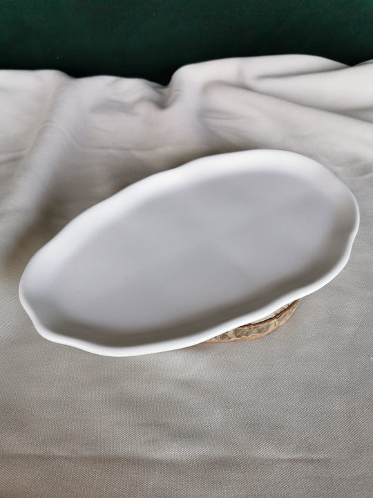 Weiße, handgefertigte flache Keramikschale mit organisch geformtem Rand, auf Holzuntergrund – minimalistisches Dekotablett für moderne Wohnräume.