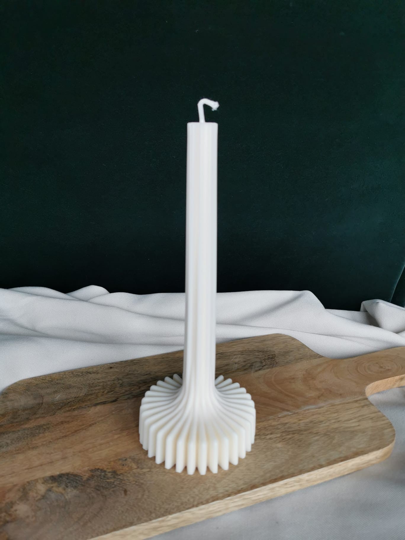 „Design-Stabkerze mit strukturiertem Wellenfuß auf Holzbrett – elegante handgegossene Deko-Kerze“