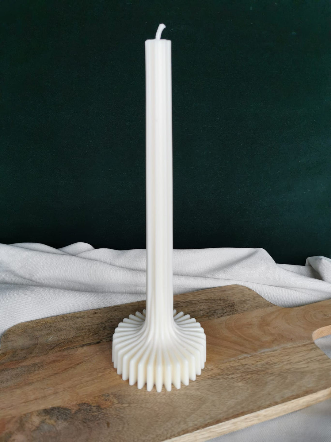Moderne Stabkerze mit strukturiertem Wellenfuß auf Holzboden, dekorativ präsentiert