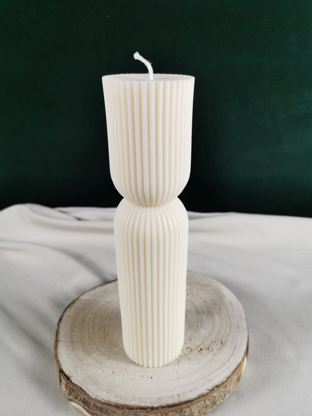 „Handgegossene cremefarbene Rapswachskerze in modernem geripptem Design, elegant geformt aus zwei verbundenen Zylindern, dekorativ auf einer Holzscheibe präsentiert.“