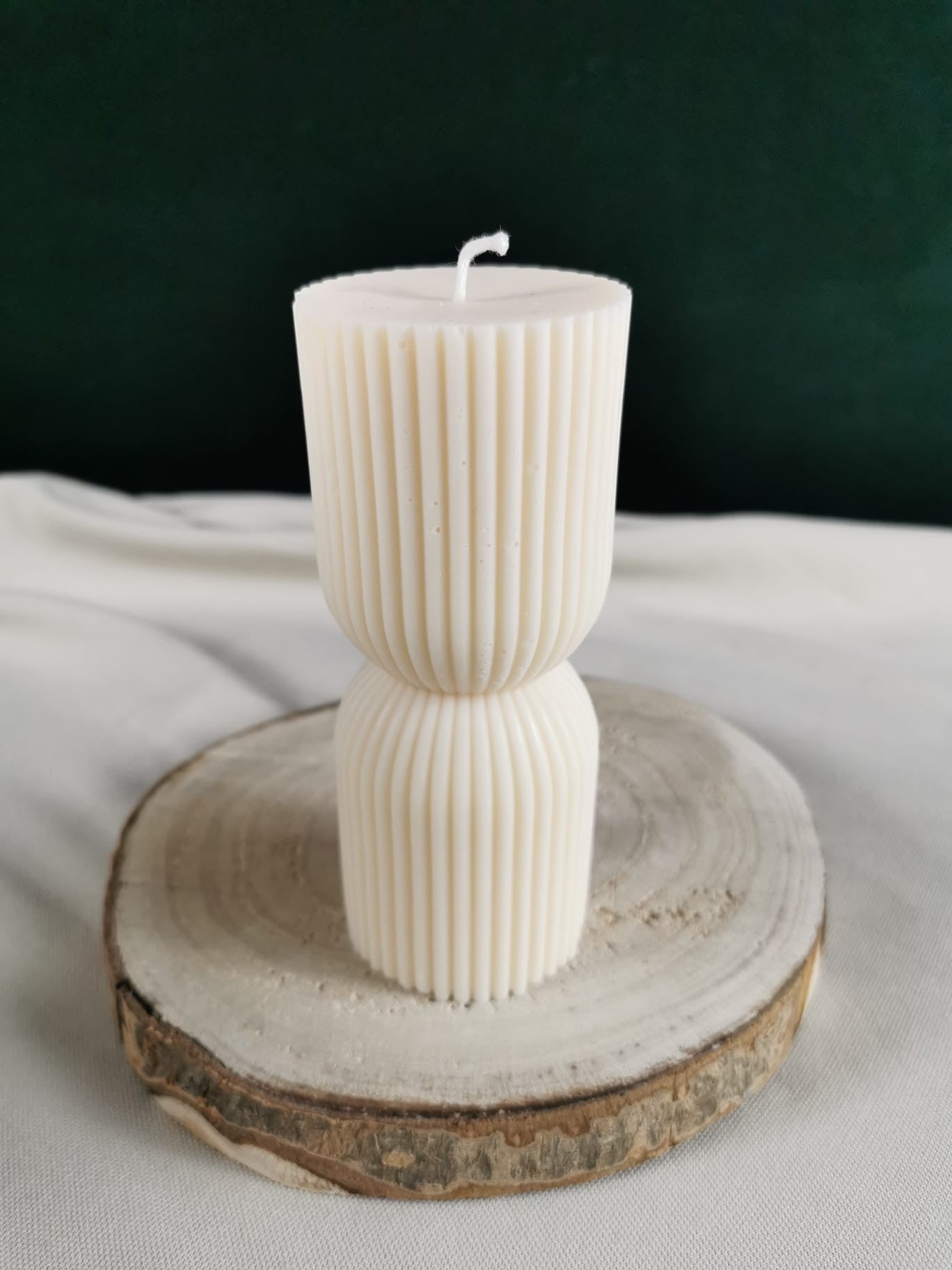 „Handgegossene cremeweiße Rapswachskerze mit elegantem doppeltem Rippen-Design, dekorativ auf einem Holzbrett präsentiert.“