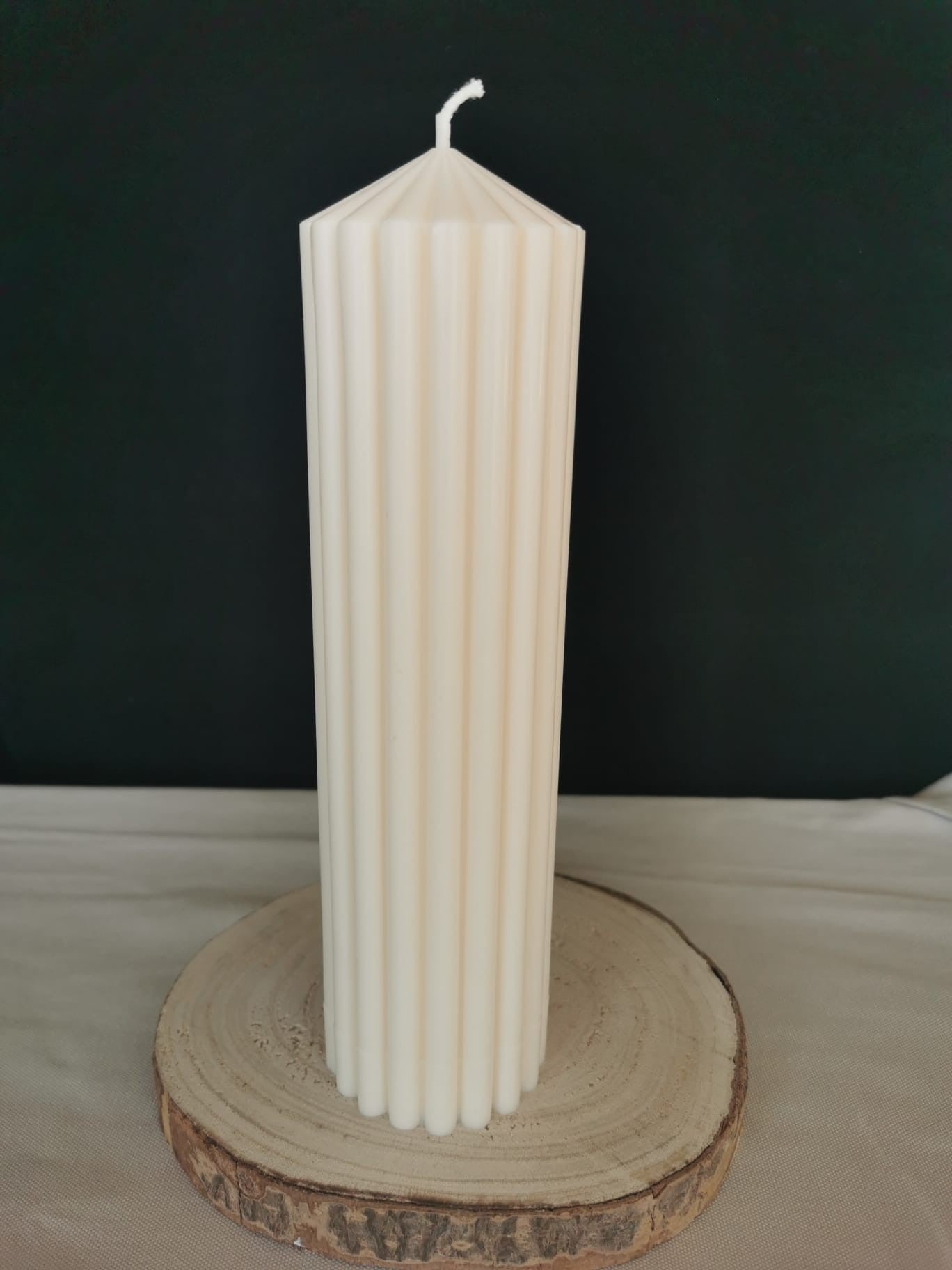 Elfenbeinfarbene Stumpenkerze mit Rillenstruktur auf Holzunterlage – handgegossene Kerze von Mara’s Kreativkischdle