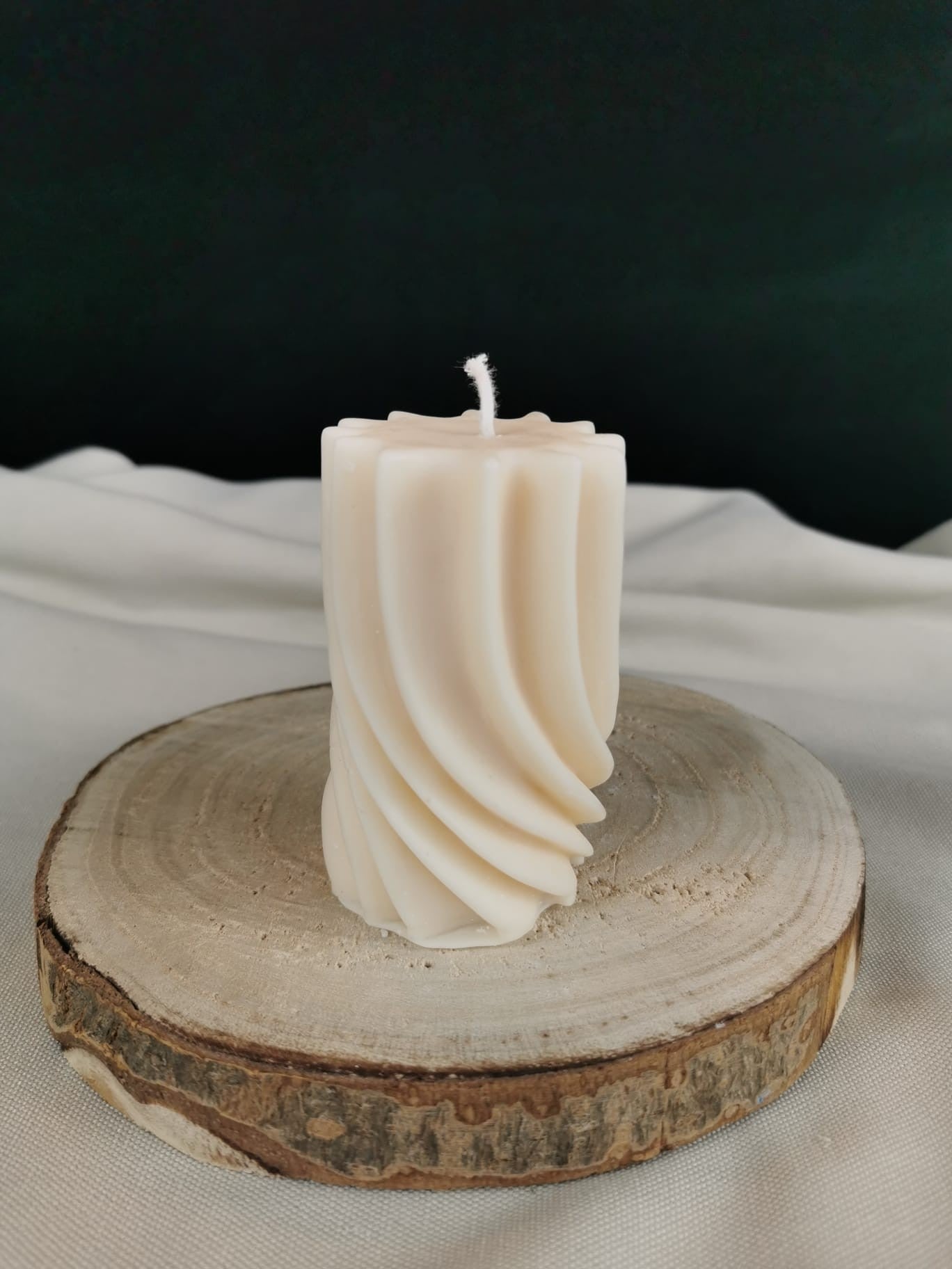 Handgemachte gedrehte Stumpenkerze aus naturbelassenem Rapswachs, dekorativ auf einer Holzscheibe präsentiert.