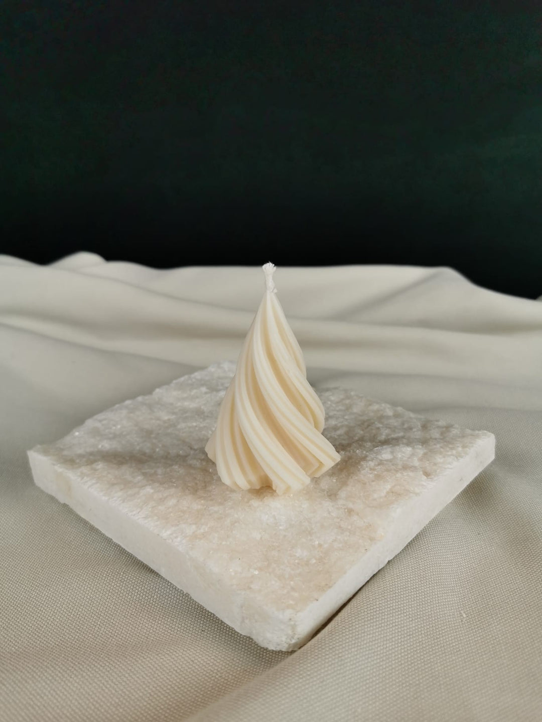 „Handgegossene gedrehte Mini-Tannenbaum-Kerze aus naturreinem Rapswachs auf heller Steinplatte – dekorative Winter- & Weihnachtskerze.“