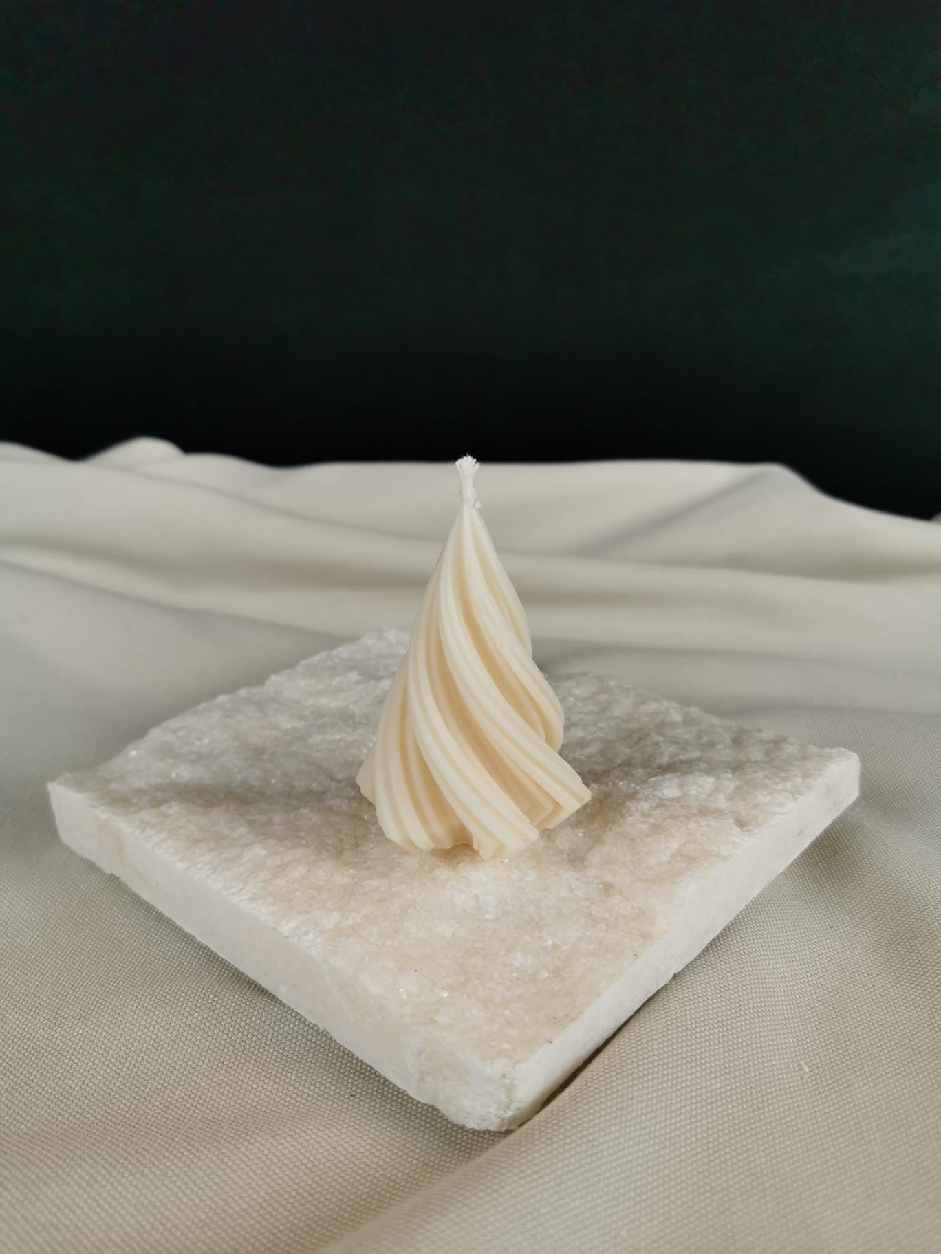 „Handgegossene gedrehte Mini-Tannenbaum-Kerze aus naturreinem Rapswachs auf heller Steinplatte – dekorative Winter- & Weihnachtskerze.“