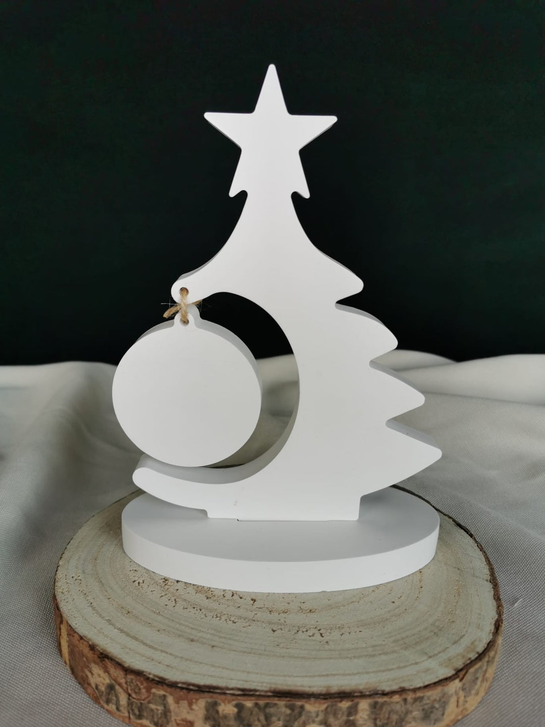 „Weißer minimalistischer Holz-Weihnachtsbaum mit rundem Anhänger auf Holzunterlage.“