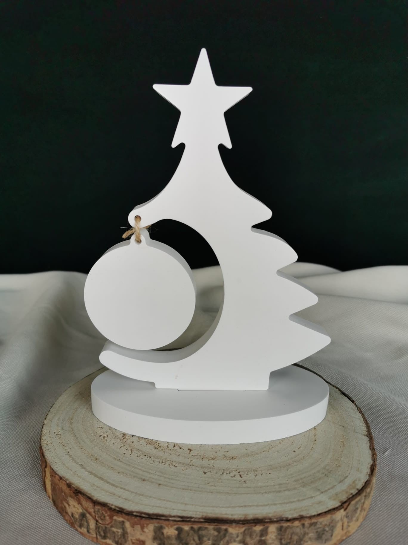 „Weißer minimalistischer Holz-Weihnachtsbaum mit rundem Anhänger auf Holzunterlage.“