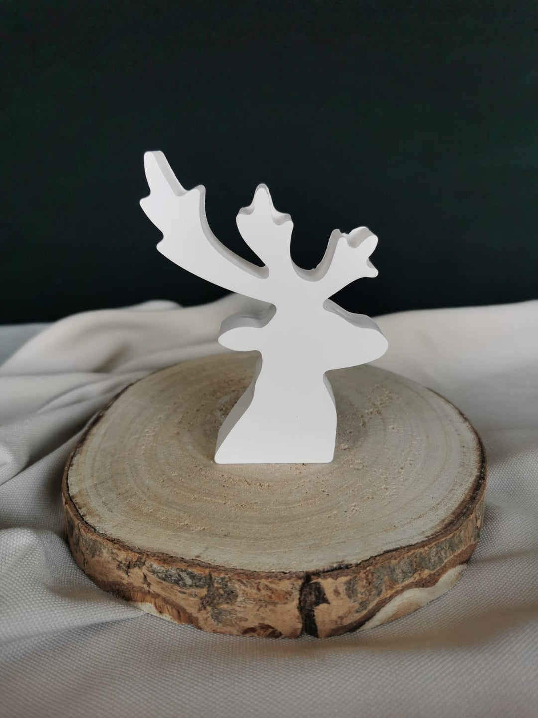 Weißer Keramik Rentier-Aufsteller in minimalistischem Design auf Holzscheibe – winterliche Weihnachtsdekoration.