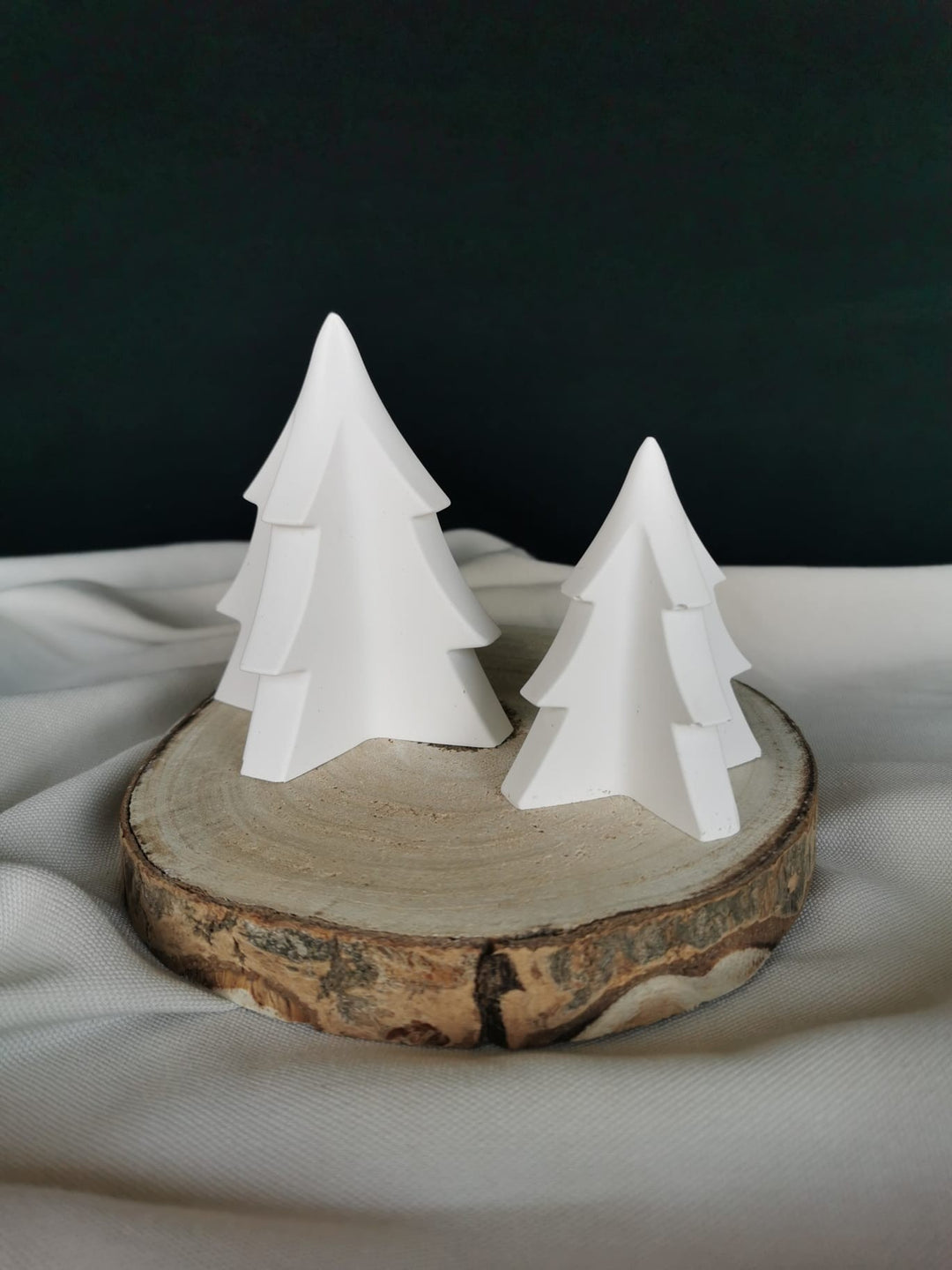 „Zwei weiße Keramik Tannenbäume in minimalistischem 3D-Design auf einem Holzpodest als moderne Weihnachtsdekoration.“