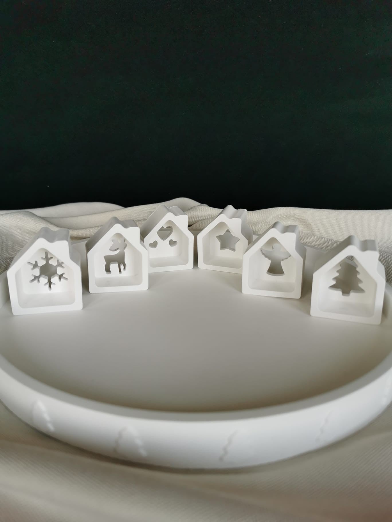 „Weiße Keramik Mini-Häuschen mit winterlichen Motiven – moderne Weihnachtsdeko auf rundem Tablett.“
