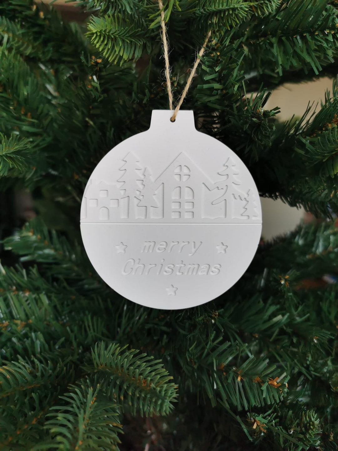 „Handgefertigte runde Keramik-Weihnachtskugel mit Winterlandschaft und Merry-Christmas-Prägung am Weihnachtsbaum“