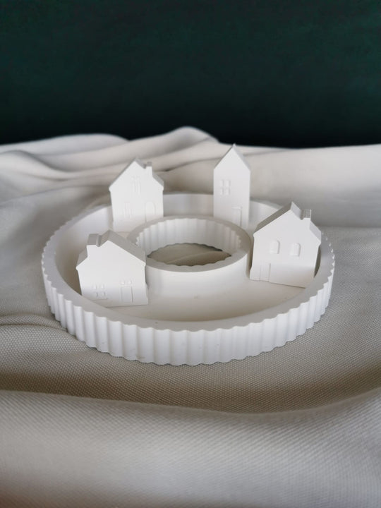 „Weißes Keramik-Winterdorf mit vier Häusern im Kreis auf rundem Tablett – moderne minimalistische Weihnachtsdeko“