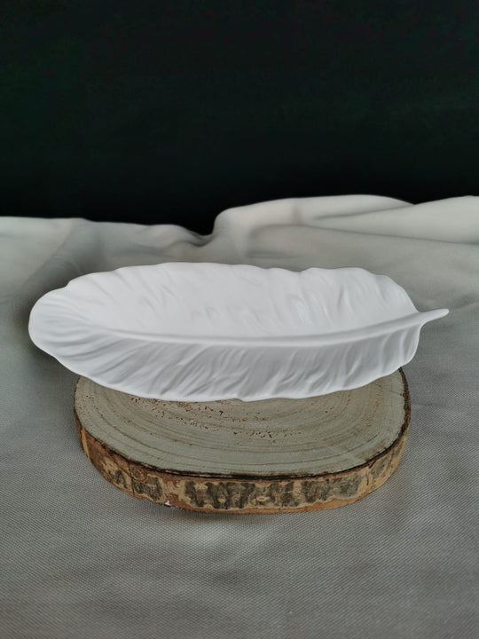 Weiße, handgefertigte Keramikschale in Federform mit feiner Struktur, auf Holzuntergrund platziert – elegante Dekoschale oder Ablagetablett für moderne Wohnräume