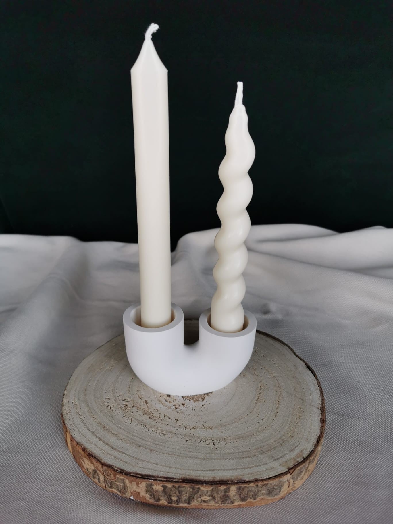 Weißer, handgefertigter Kerzenhalter in moderner U-Form aus Keramik oder Beton, auf Holzuntergrund – minimalistisches, nachhaltiges Wohnaccessoire mit Kerzen
