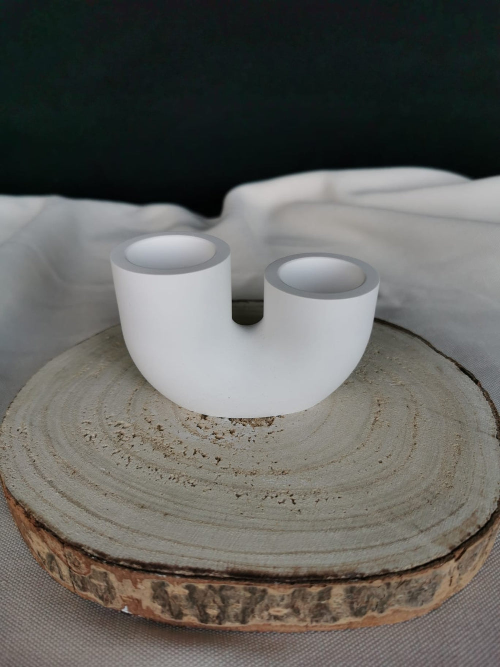 Weißer, handgefertigter Kerzenhalter in moderner U-Form aus Keramik oder Beton, auf Holzuntergrund – minimalistisches, nachhaltiges Wohnaccessoire